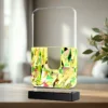 Abstract geometric glass sculpture with a pale frame top and a multicolored mosaic body on a black pedestal.