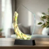Colorful glass sculpture award on a black pedestal in a bright room.